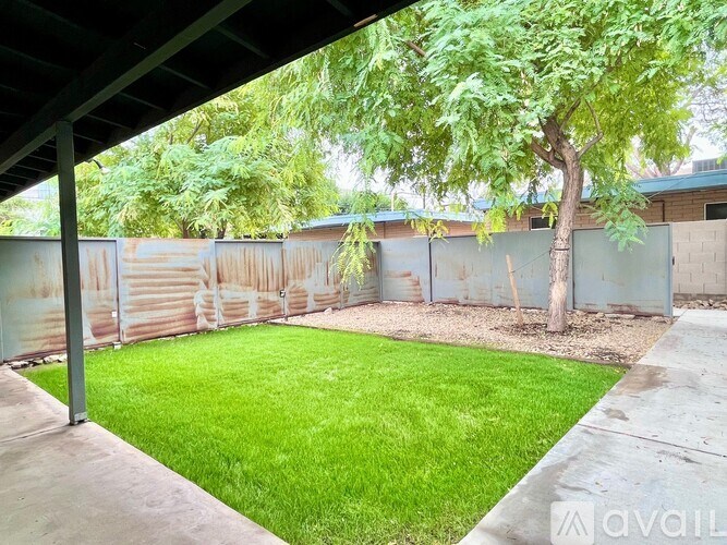 A backyard with a green lawn and a tree.