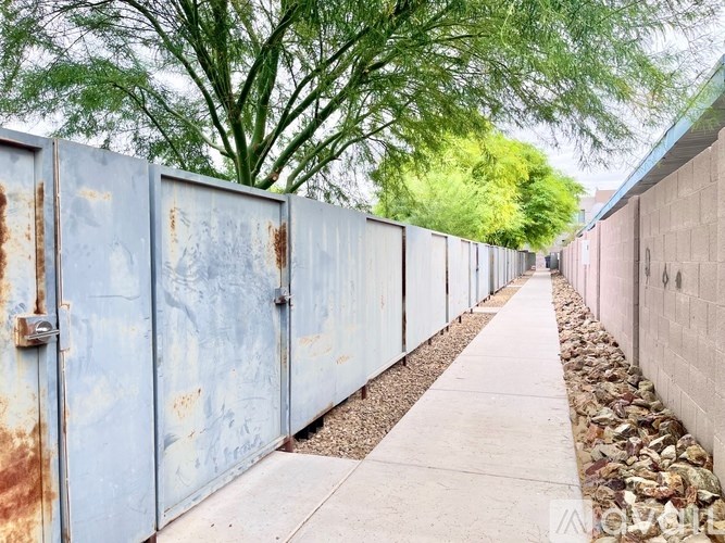 A row of rusted metal gates with a concrete pathway in between.