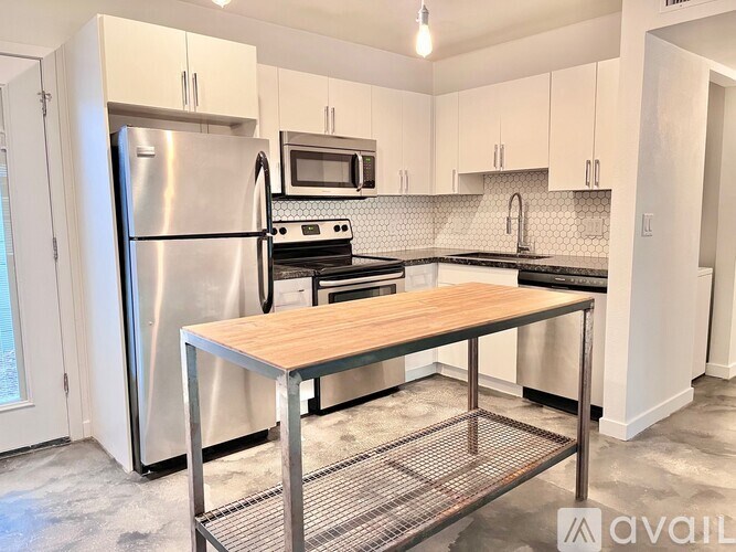 A kitchen with a stainless steel refrigerator, microwave, oven, and a wooden top island.
