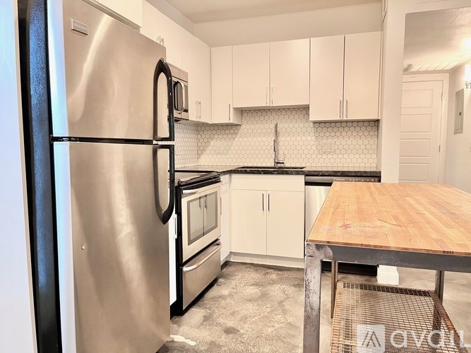 A kitchen with a stainless steel refrigerator and white cabinets.