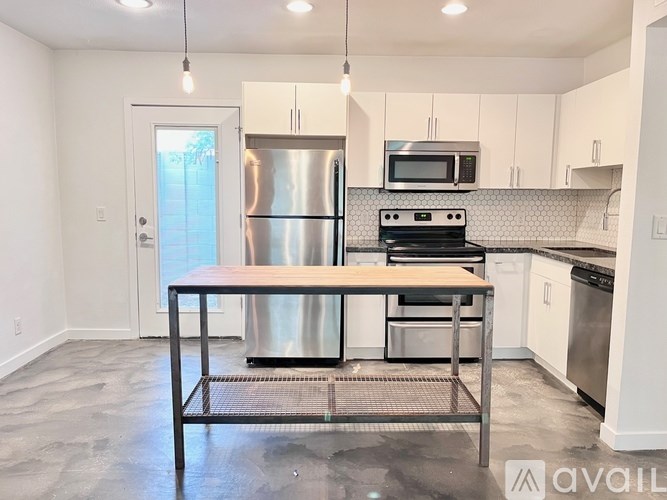 A kitchen with a table in front of a stainless steel refrigerator and oven.