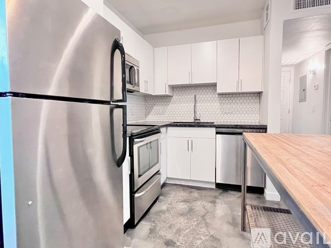 A kitchen with a stainless steel refrigerator and white cabinets.