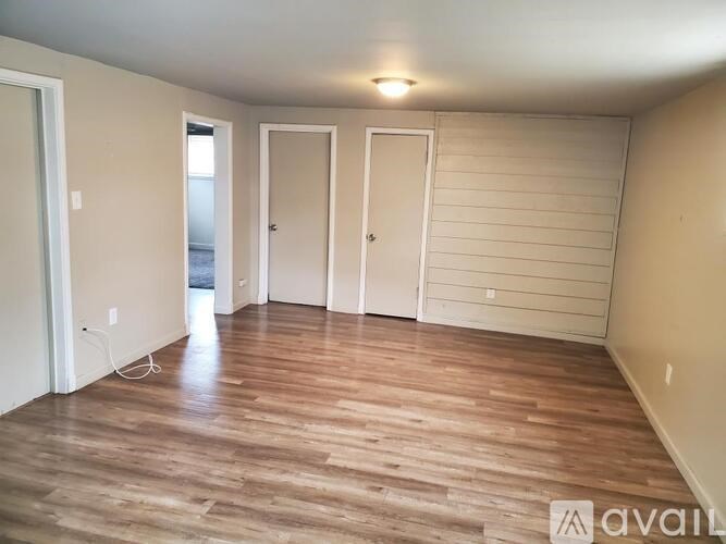 A room with wooden flooring and three doors.