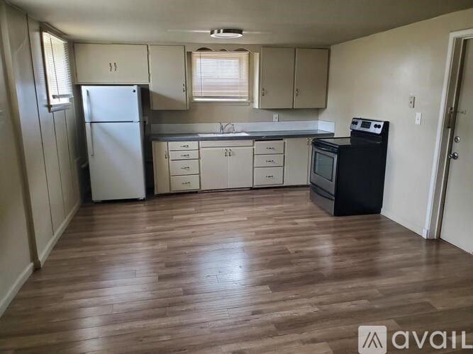 A kitchen with white appliances and wooden floors.