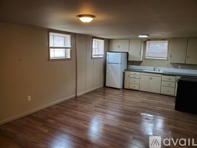 A kitchen with a refrigerator, cabinets, and a countertop.