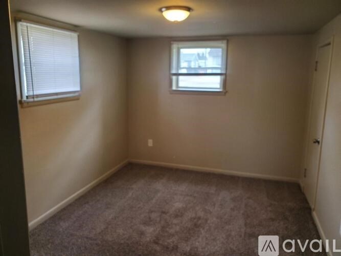 A small, empty room with a carpeted floor and a window with blinds.