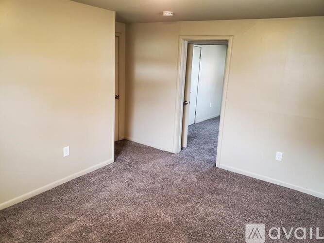 A carpeted room with a doorway leading to another room.