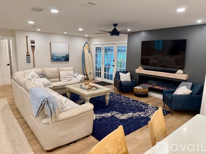 A living room with a surfboard leaning against the wall.