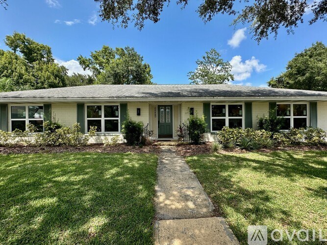 A house with a green lawn and trees in the background.