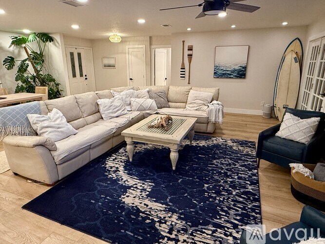 A living room with a white couch, a coffee table, and a blue rug.