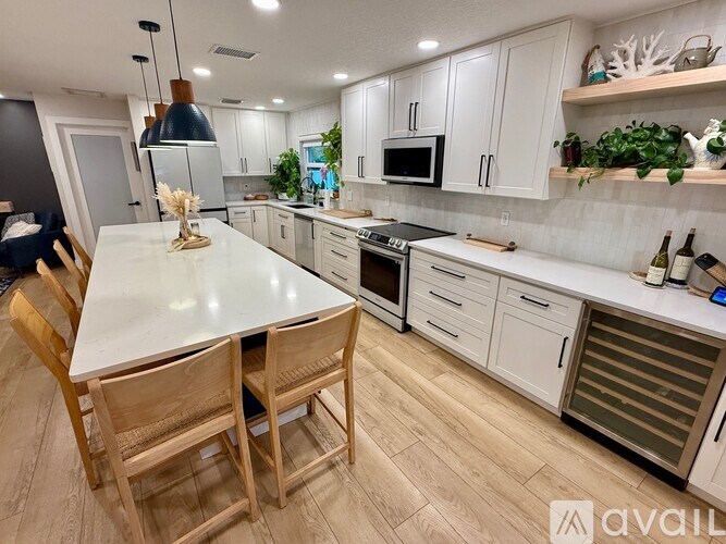 A kitchen with a table and chairs in the foreground and a refrigerator, microwave, and oven in the background.
