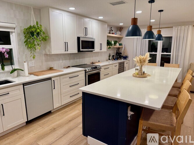 A kitchen with a white countertop and wooden chairs.