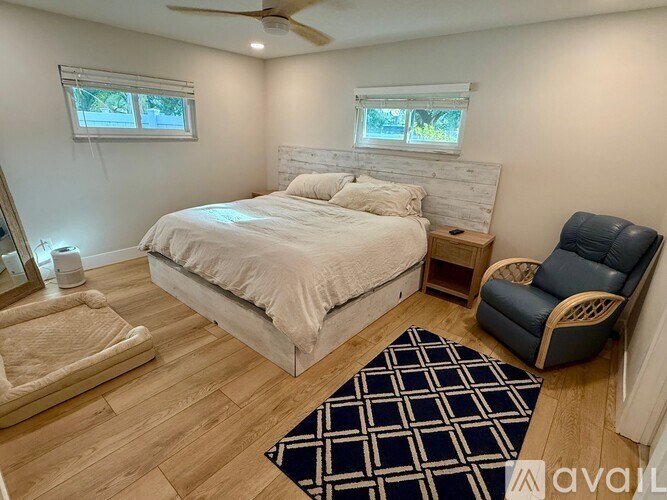 A bedroom with a bed, chair, and rug.