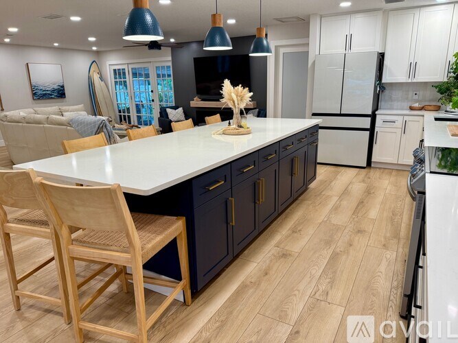A modern kitchen with a large island and wooden chairs.