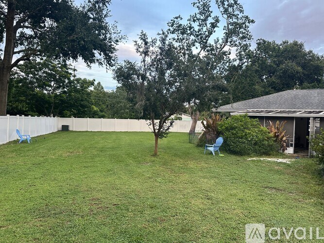 A backyard with a white fence and a tree in the middle.