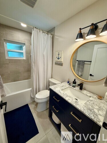 A bathroom with a white toilet, a sink, a mirror, and a shower.