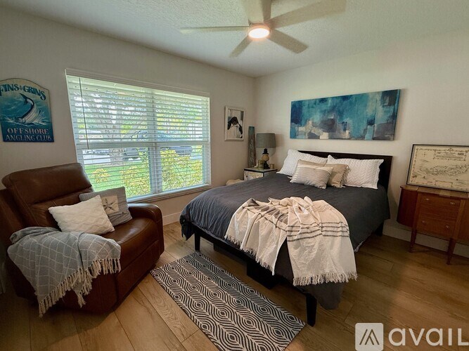 A bedroom with a bed, chair, and window.