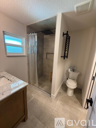 A bathroom with a toilet, sink, and shower.