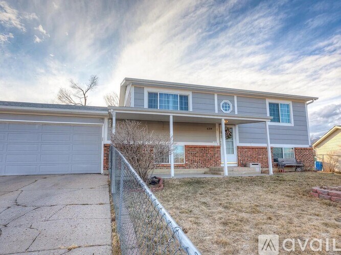 A house with a grey garage door and a brick wall.