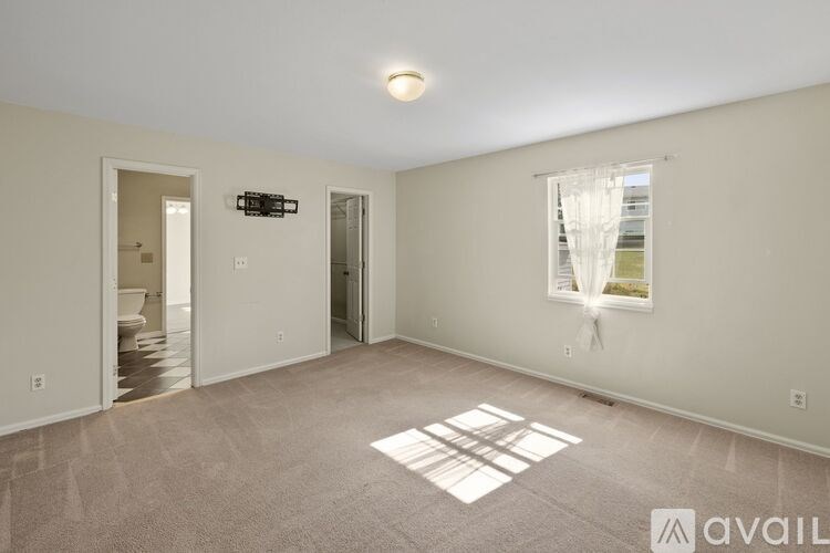 A spacious room with a window and a carpeted floor.