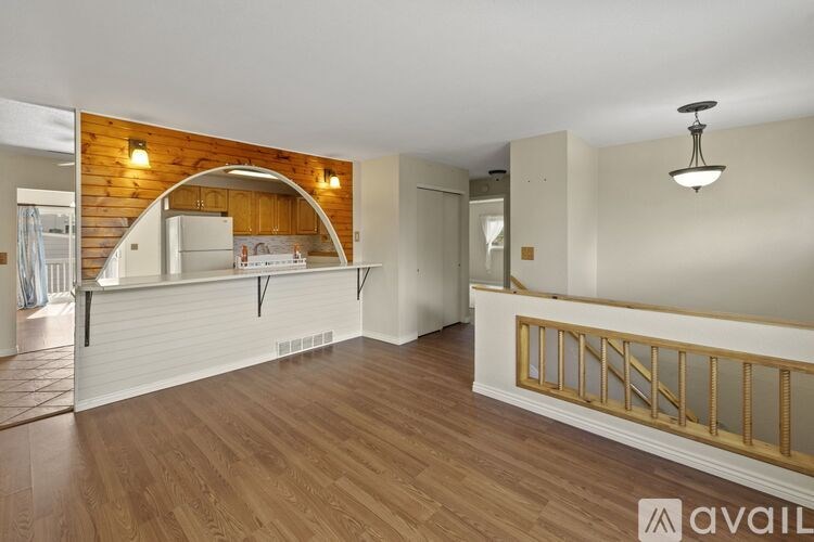 A spacious room with wooden floors and a balcony with a railing.