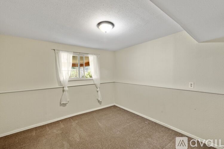 A room with a window covered by a white curtain.