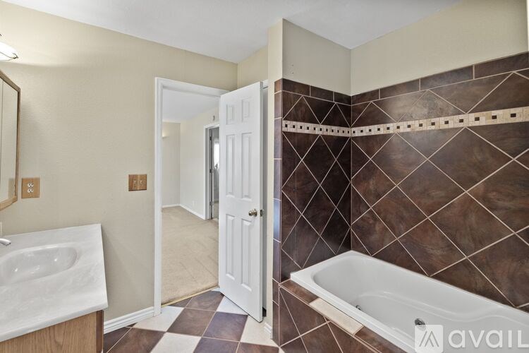 A bathroom with a white door and a brown tiled wall.