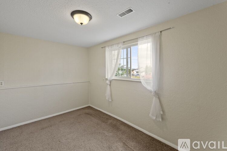 A room with a window covered by white curtains.