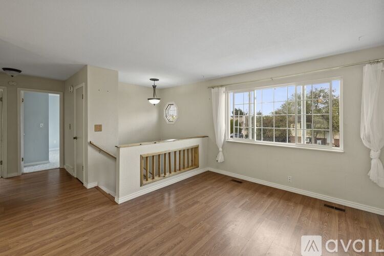 A room with wooden floors and a window with white curtains.