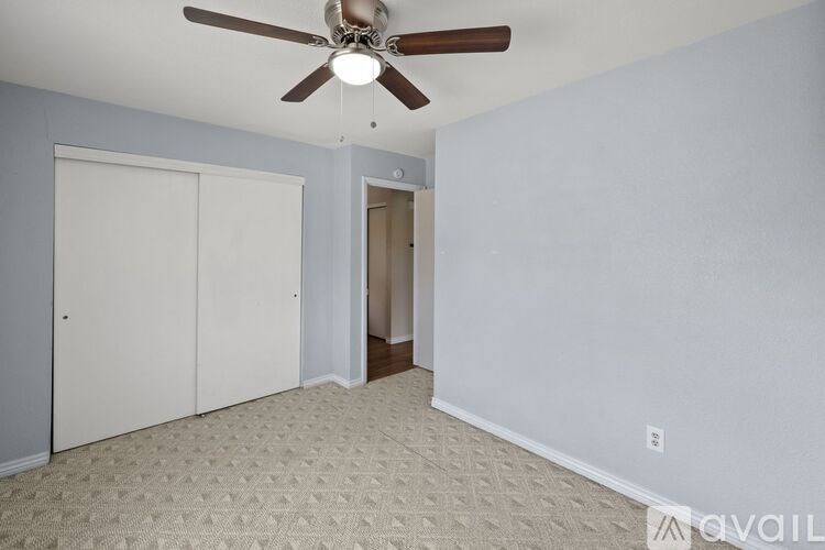 A room with a ceiling fan and carpeted floor.