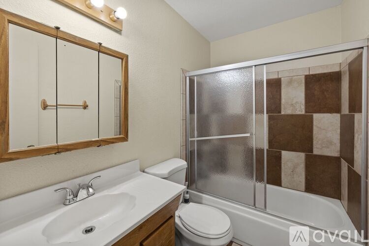 A bathroom with a white sink, toilet, and a glass shower stall.