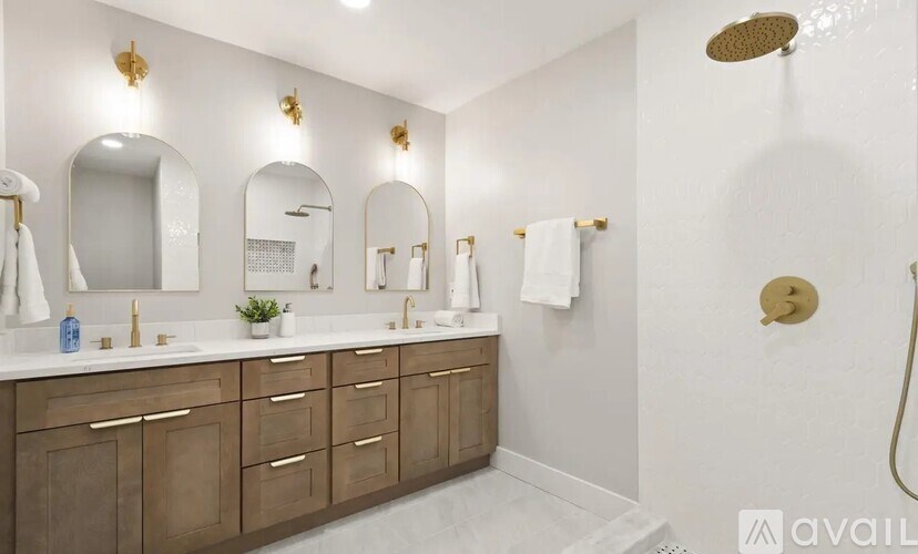 A bathroom with a white and gold color scheme and a large mirror above the sink.