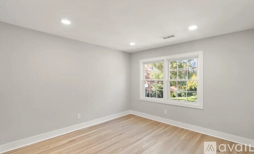 A room with a window showing a view of trees and a house.