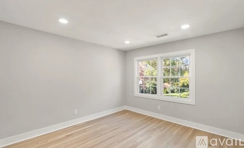 A room with a window showing a view of trees and a house.