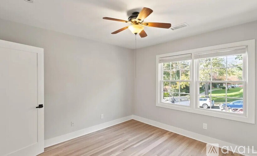 A room with a ceiling fan and a window overlooking a street.