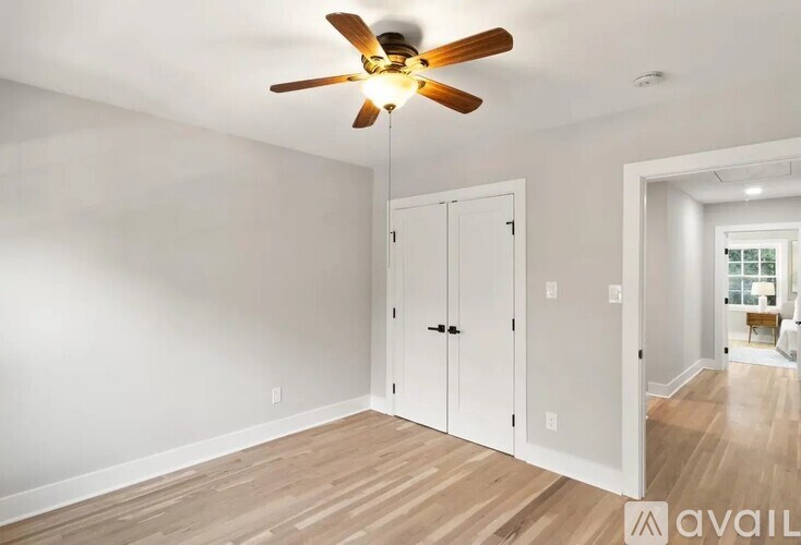 A room with a ceiling fan and a white door.