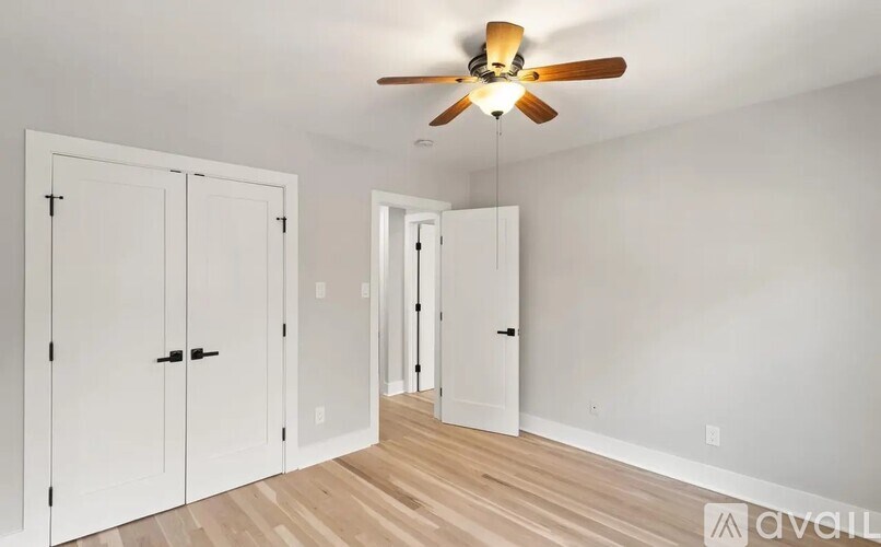 A room with a ceiling fan and three white doors.