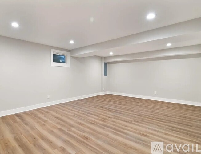 A spacious room with wooden flooring and recessed lighting.