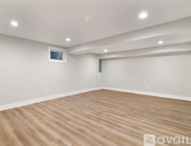 A spacious room with wooden flooring and recessed lighting.