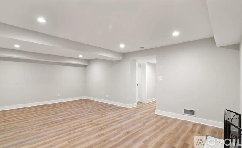 A spacious room with wooden flooring and white walls.