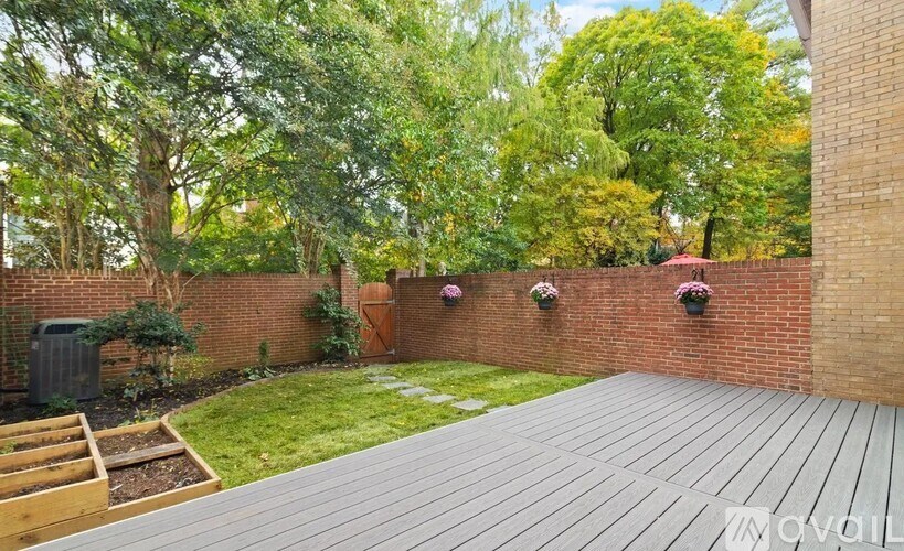 A backyard with a wooden deck and a brick wall.