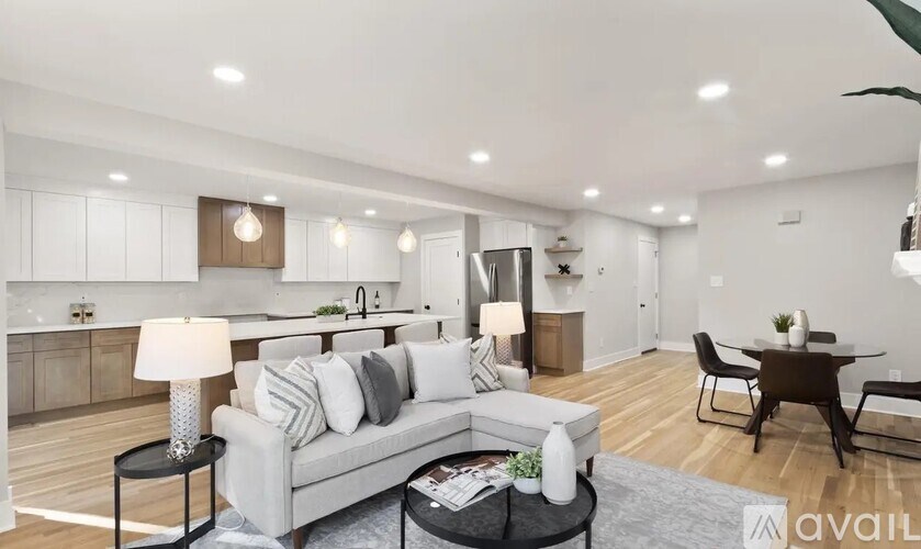 A modern living room with a grey sofa, a black coffee table, and a dining table with chairs.