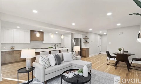 A modern living room with a grey sofa, a black coffee table, and a dining table with chairs.