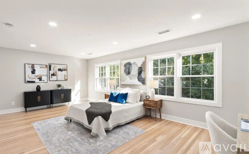A bedroom with a large bed, a nightstand, and a window.