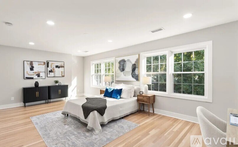 A bedroom with a large bed, a nightstand, and a window.