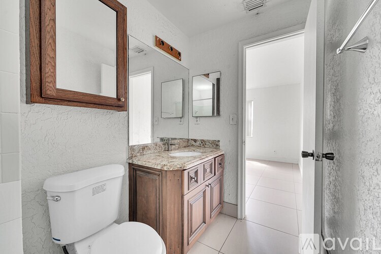 A bathroom with a toilet, sink, and mirror.