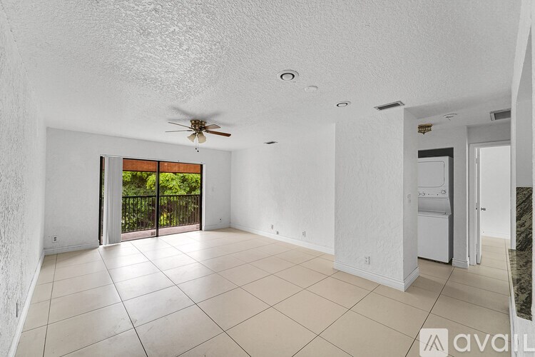 A spacious room with a ceiling fan and sliding glass doors leading to a balcony.