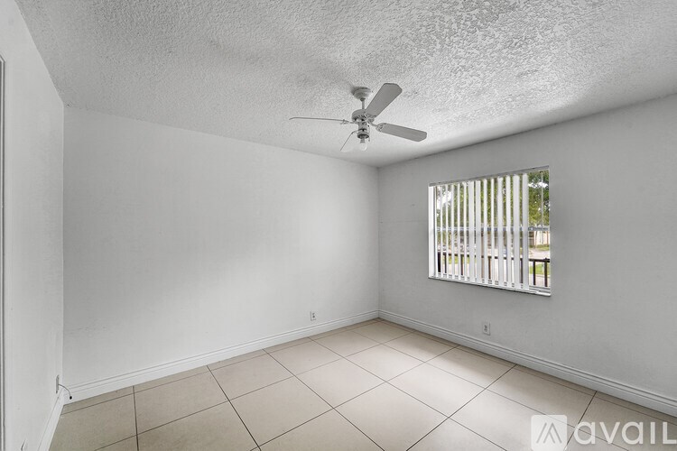 A room with a ceiling fan and a window with blinds.