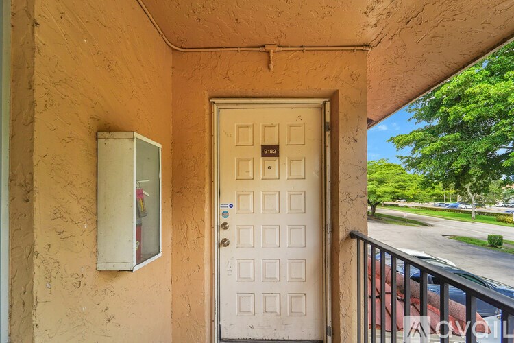 A white door with a mail slot and a mailbox on a tan wall.