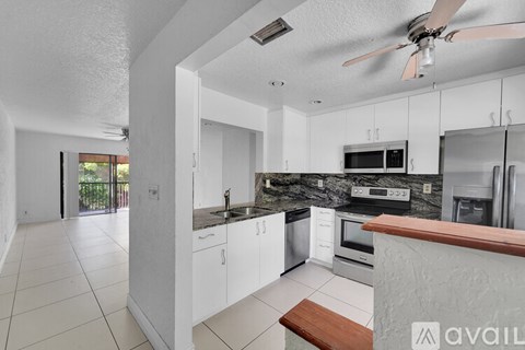 A modern kitchen with white cabinets and a wooden counter.
